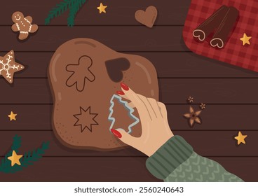 Woman cutting a tree-shaped cookie from gingerbread dough, surrounded by cookies, cinnamon, and pine branches on a wooden surface. cozy Christmas vibe
