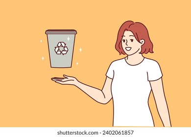 Woman displays trash can with recycling symbol and calls for sorting garbage to take care environment. Eco activist girl talks about importance of waste recycling to avoid CO2 emissions