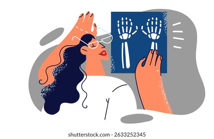 Woman doctor examines x-ray shot of hands of person injured or suffering from carpal tunnel syndrome. Girl doctor radiologist in medical uniform works in hospital helping surgeon to treat people 