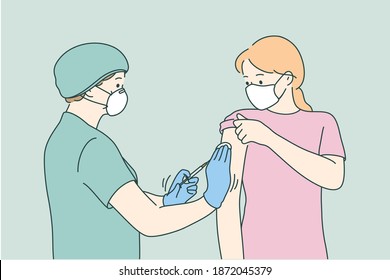 Woman doctor in protective medical mask and uniform holding syringe before making injection to young female patient in medical clinic. Vaccination, Covid-19 coronavirus vaccine concept 