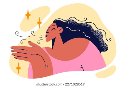 Woman does breathing exercise to support lung health and raises palm to face. Positive woman with long hair blowing on hands to warm up or enjoy pleasant breath after eating flavored chewing gum