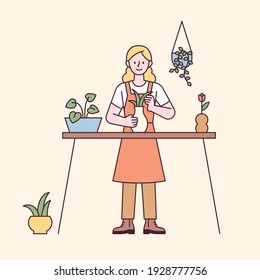 Una mujer está haciendo jardinería en la mesa. estilo de diseño plano ilustración vectorial mínima.