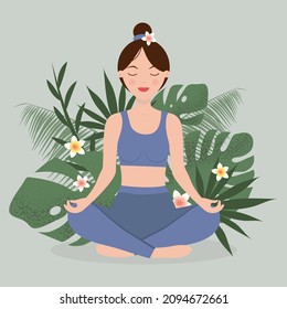 Woman doing yoga in lotus position, against the background of tropical leaves and flowers. Meditation concept.