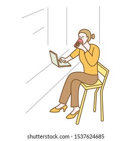 Woman is dringking while checking email on a laptop.
