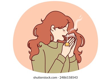 La mujer bebe té caliente de cristal transparente, disfrutando del sabor de la bebida caliente en el Clima frío del invierno. Chica joven en suéter se siente acogedor y bebe té tomar un descanso para descansar del trabajo