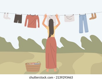 woman drying clothes outside. drying clothes in the morning in outdoor. tree. park. concept of house chores.