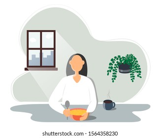 woman eating food, young man sitting at the table and having breakfast. In a bowl of porridge, next to a Cup of hot tea or coffee. The sun shines brightly through the window.