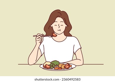 Woman eats appetizing fresh vegetable salad and closes eyes, enjoying delicious and healthy diet. Girl has lunch or dinner with vegetables, according to advice of nutritionist, recommended new diet