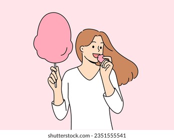 Woman eats cotton candy, enjoying airy sugar dessert while walking in park or at fair. Carefree girl holding cotton candy and experiencing positive emotions from lack of important things to do