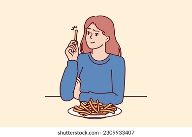 Woman eats french fries without thinking about health risks of fast food and fried snacks. Girl is having lunch in cafe sitting at table with french fries and needs consultation with nutritionist