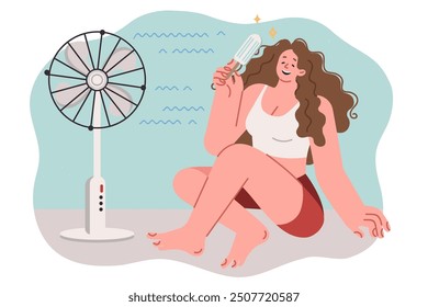 Woman eats ice cream and sits on floor near electric fan, cooling off during sudden warming of summer. Girl relaxes and laughs, cooling off after returning from walk along hot street