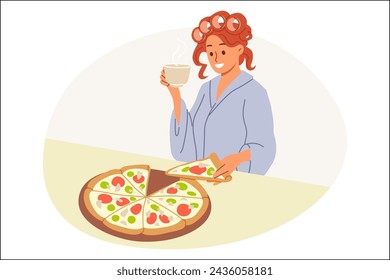 Woman eats italian pizza and drinks coffee delivered from pizzeria, standing in kitchen of house in curlers and bathrobe. Girl has breakfast with pizza, enjoying taste of traditional italian pie