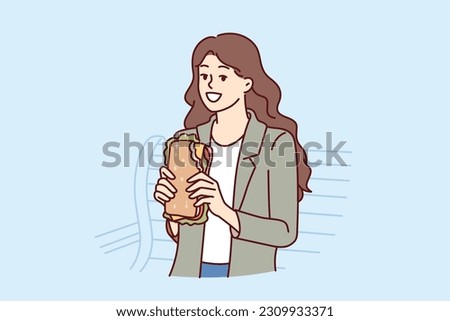 Woman eats sandwich while sitting on bench in park and enjoying street food and good weather. Young smiling city girl with cheese sandwich takes break from walking to eat and gain strength