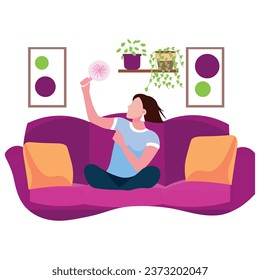 Woman with electric fan sitting on sofa at home