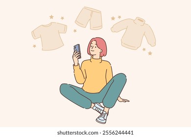 Woman is engaged in online shopping, buying clothes via internet on mobile phone. Girl selects wardrobe items on smartphone, sits on floor and enjoys shopping in app with home delivery