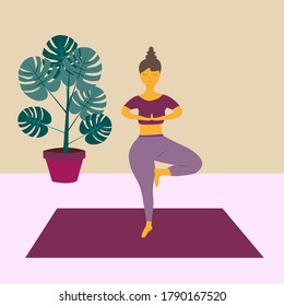 The woman is engaged, standing on the rug. Indoor yoga, tree pose, Vrksasana. Balance on one leg. Training of the vestibular apparatus. Strengthening the muscles of the abdomen, arms and legs.