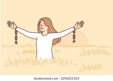 Woman feels freedom and happiness standing in field among tall grass and waving arms with fragments of chains. Girl freed from chains enjoys walking in ecologically clean place not spoiled by people