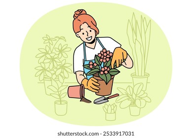 Florista de la mujer se encarga de las plantas caseras y sostiene la maceta con flor de color violeta floreciente de pie cerca de la mesa. Chica en delantal disfruta de trabajo como florista, y hace carrera como vendedor en tienda o invernadero