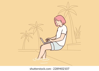 Woman freelancer working with laptop sitting on beach under palm tree or near pool in resort hotel. Successful girl freelancer performs remote work via Internet during relaxing on beach 