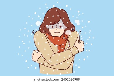 Woman freezes standing under snow in cold winter weather, dressed in sweater and needs warm down jacket or raincoat. Girl is freezing due to lack of outerwear and risks catching cold and flu