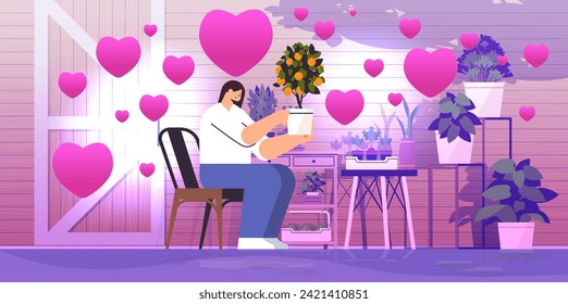 woman gardener taking care of potted orange plant at backyard home garden with pink love hearts happy valentines day celebration