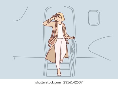 Woman gets off airplane, having arrived on business trip on private flight to conclude important contract. Girl airplane passenger puts on sunglasses after arriving at airport at destination