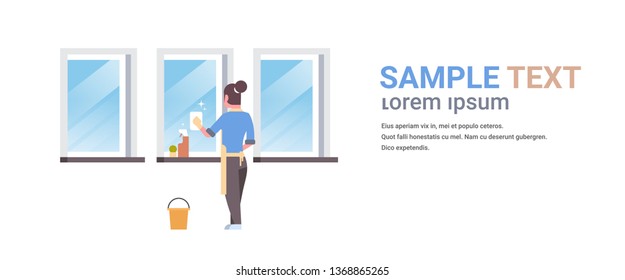 woman in gloves and apron cleaning windows with rag cleaner spray rear view housewife doing housework concept flat horizontal copy space white background full length