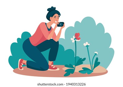 A woman in a green meadow photographs a butterfly on a flower.