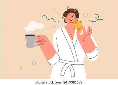 Woman is having breakfast, eating fresh croissant and holding cup of coffee in hand, standing in bathrobe. Girl has breakfast after waking up enjoying taste of homemade cakes and caffeinated drink.