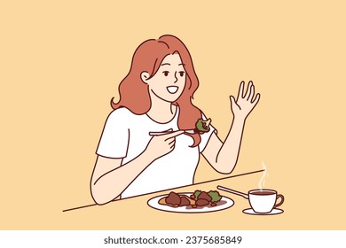 Woman is having lunch in cafe sitting at table and raising hand up to call waiter. Cafe visitor girl eats steamed vegetables to avoid passing fatty and caloric food causing weight gain