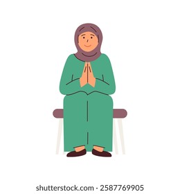 A woman in a hijab sits serenely her hands clasped in prayer