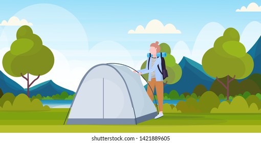 woman hiker camper installing a tent preparing for camping hiking concept traveler on hike beautiful nature landscape background full length flat horizontal