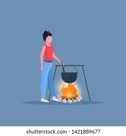 woman hiker cooking meals girl preparing food in boiling pot at campfire hiking camping concept female traveler on hike full length flat