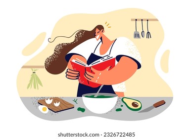 Woman is holding cookbook standing near kitchen table and preparing healthy breakfast from natural products. Girl housewife in apron learn to cook from cookbook with recipes and helpful tips