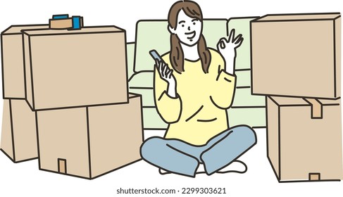 
A woman holding a smartphone in front of cardboard and giving OK