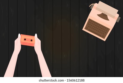 Woman holds audio cassette in her hands. Typewriter and retro audio cassette on black wooden background. Template for text