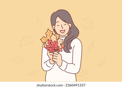 Woman holds autumn foliage of different colors in hands, collecting tree leaves to create herbarium. Girl rejoices at arrival of autumn and opportunity to find beautiful leaves from trees in park