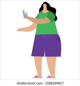 A woman holds a glass of water with lemon in her hand