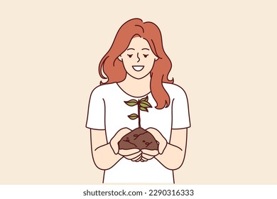 Woman holds handful of earth with plant drawing attention to problem of ecology and pollution or CO2 emissions. Happy girl doing plant cultivation and care for environment or ecology as volunteer