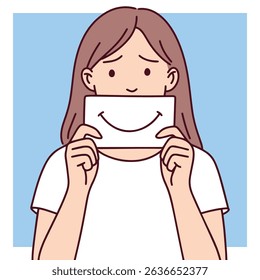 Woman holds paper smile in front of face, hiding her true emotions. Visual metaphor of depression, masking pain, and pretending to be okay