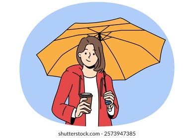 Woman holds plastic cup with coffee takeouts and umbrella protecting from rain during autumn walk. Girl enjoys taste of invigorating takeouts coffee and looks at screen with thoughtful grin.