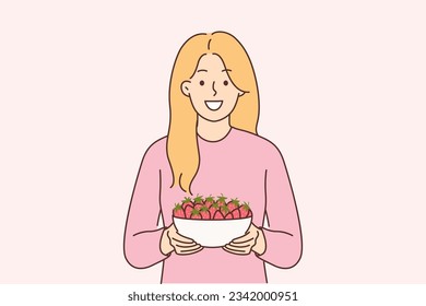 Woman holds plate of strawberries and smiles, offers to try fresh berries and farm fruits. Girl with smile looks at screen recommending eating organic strawberries containing antioxidants