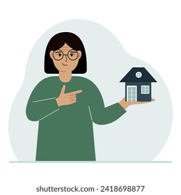 A woman holds a small house in his palm. Concepts of inheritance, real estate transfer, mortgage, credit, loan or house purchase.