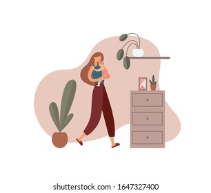 Woman hugging baby at home. Loving mother in casual clothes carrying and embracing little baby while walking near cabinet with decorations and potted plants in cozy room at home