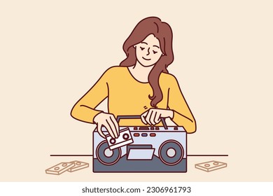 Woman inserts tape cassette into player to turn on music and start party in retro style. Happy girl with cassette recorder with smile chooses audio recording with songs from own collection 