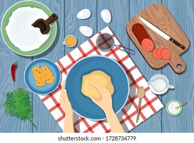 Woman kneads the dough on a blue table. View from above. Cooking pizza. Ingredients on the table.