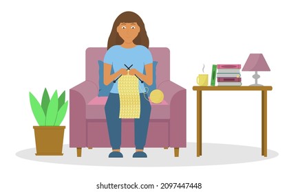 A woman knits a scarf at home sitting on a chair. Hobby.