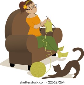 Woman knitting i an armchair and cat playing with a ball of yarn
