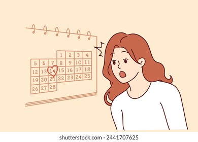 Woman learns about valentine day on february 14th and feels shocked, standing near wall with calendar. Girl forgot about approach of valentine day does not know where to get gift for boyfriend