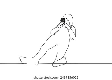 woman lies at full height with her feet towards the camera holding a phone with both hands - one line art vector. concept mobile surfing, social media addiction. Handmade vector not AI